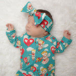 Sweet sleeping newborn baby girl wearing a cherubs printed baby romper with matching bow headband