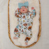 A sleeping baby girl wearing a Lottie & Lysh floral printed babygrow with matching bow turban hat.