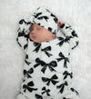 New baby girl wearing a bow print babygrow with coordinating headband. Ethically and sustainably created by Lottie & Lysh in Cornwall.
