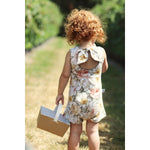 red haired little girl in a strawberry field wearing a vintage inspired floral playsuit by Lottie & Lysh