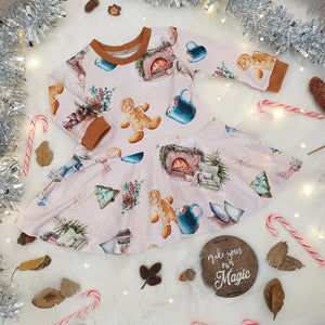 Girls Christmas Skater Dress featuring gingerbread men, hot chocolates and fireplaces against a beige background.