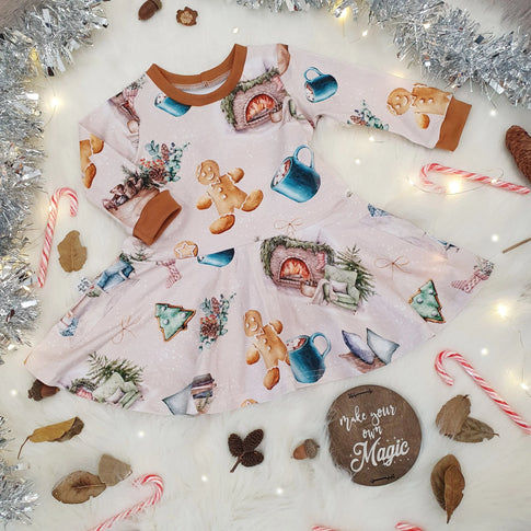 Girls Christmas Skater Dress featuring gingerbread men, hot chocolates and fireplaces against a beige background.