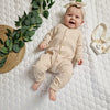smiling baby girl wearing beige ribbed babygro and headband
