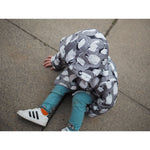small boy sitting on the floor wearing lottie and lysh penguin raincoat and rhino leggings